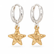 Silver hoop earrings with hammered gold star charms on a white surface