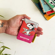 Hand holding Peanuts Rockstar Cardholder with Snoopy illustration and yellow Peanuts tag.