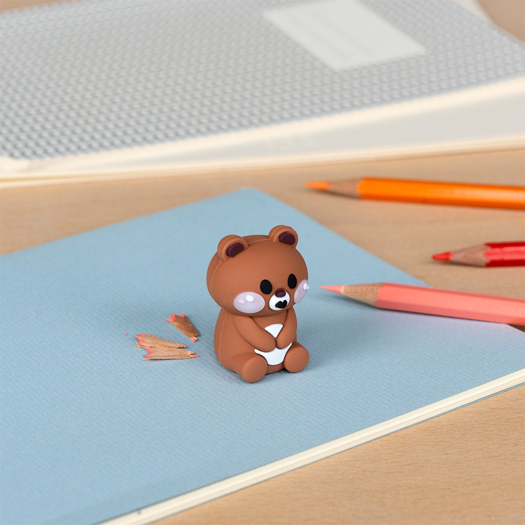 Bear pencil sharpener on a desk beside coloured pencils