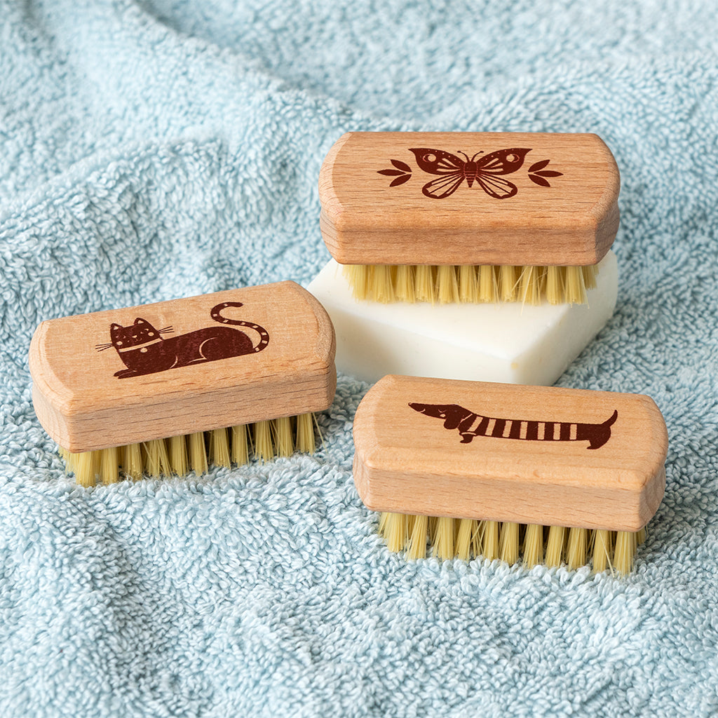 Three wooden nail brushes showing the assorted printed designs