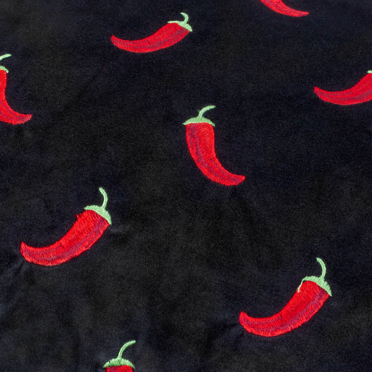 Close up of the embroidered red chillies on black velvet
