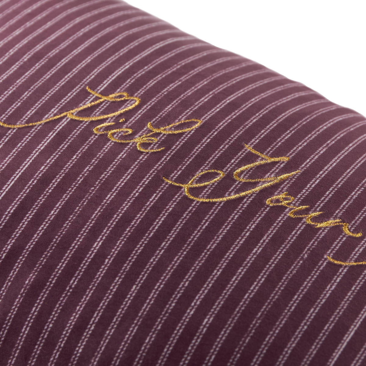 Close up of the gold Pick Your Poison embroidery on striped velvet