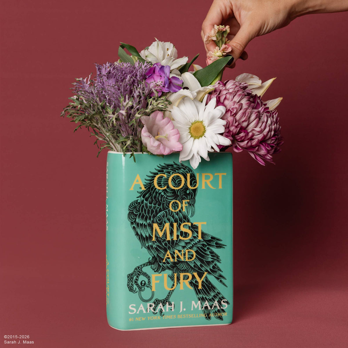 A Court of Mist and Fury Book Vase with flowers against a deep red wall