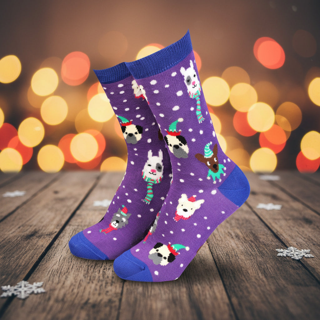 A pair of purple crew socks with blue toes and heels, featuring a pattern of small white dogs wearing colorful winter hats and scarves against a white snowy background.