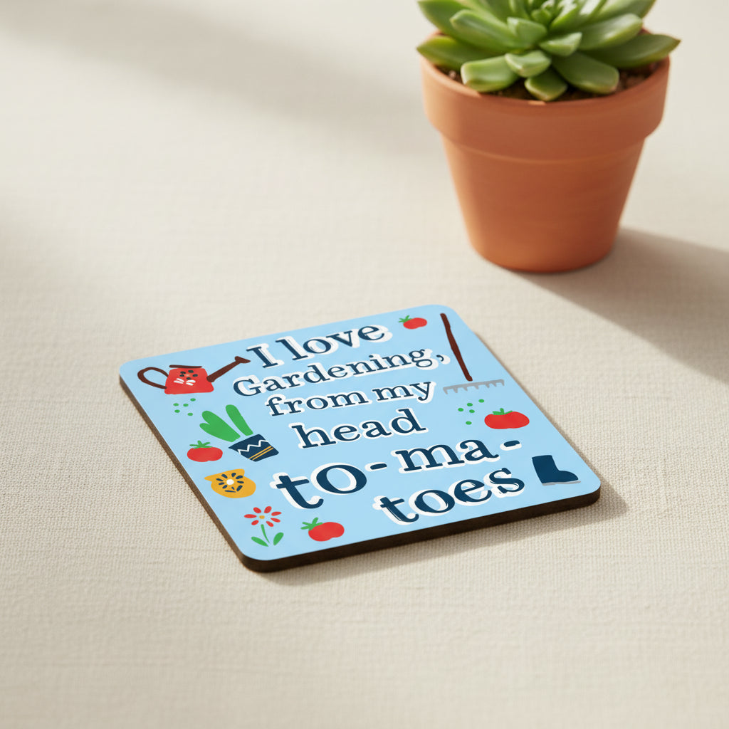 A square graphic with rounded corners featuring the phrase “I love Gardening, from my head to tomatoes” in dark blue outlined letters on a light blue background. The design includes small gardening illustrations such as a red watering can, potted tomato plants, tomatoes, flowers, a rake, and a boot.