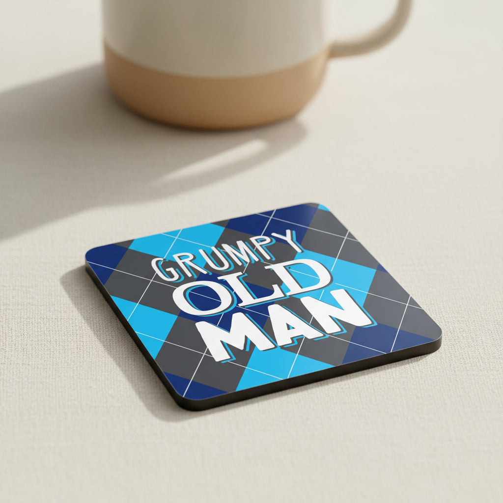 A square graphic design with rounded corners featuring the words 'GRUMPY OLD MAN' in large white letters with a blue outline, set against a blue, navy, and gray argyle pattern background.