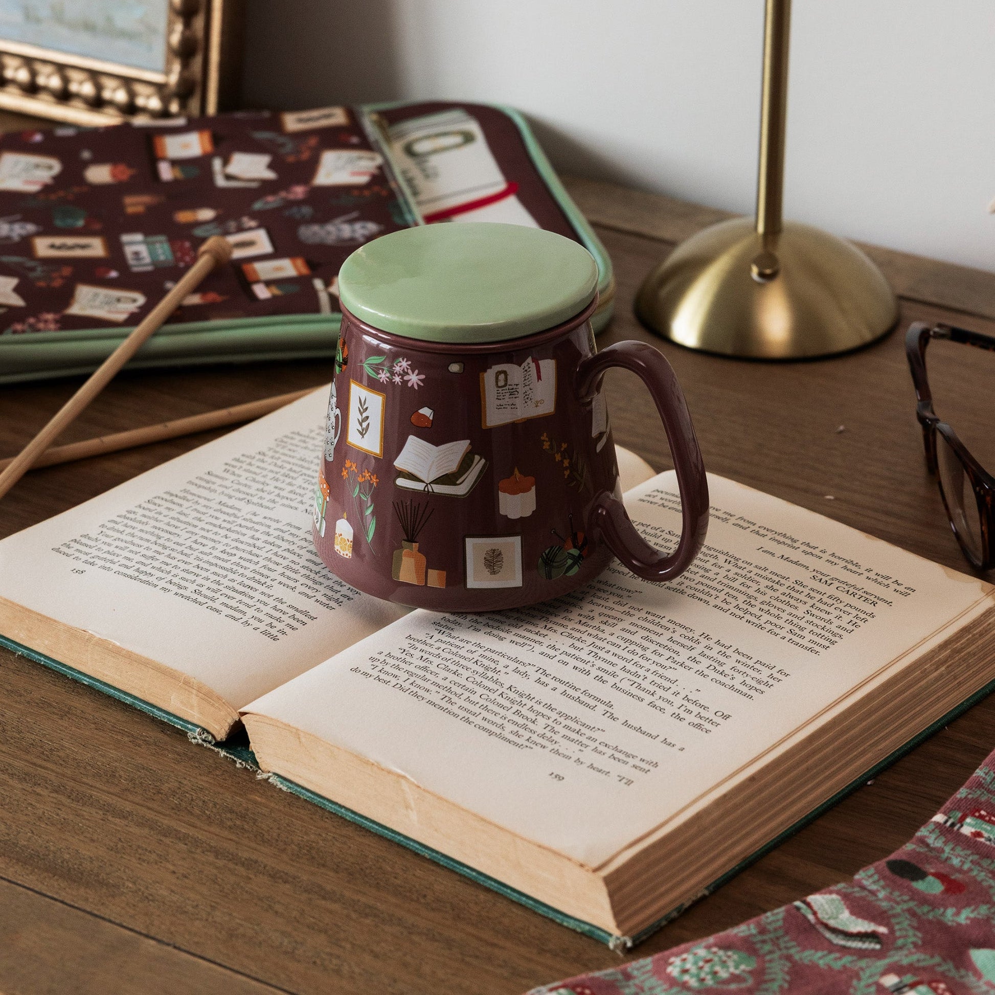 Bookish tea infuser mug with lid resting on an open book