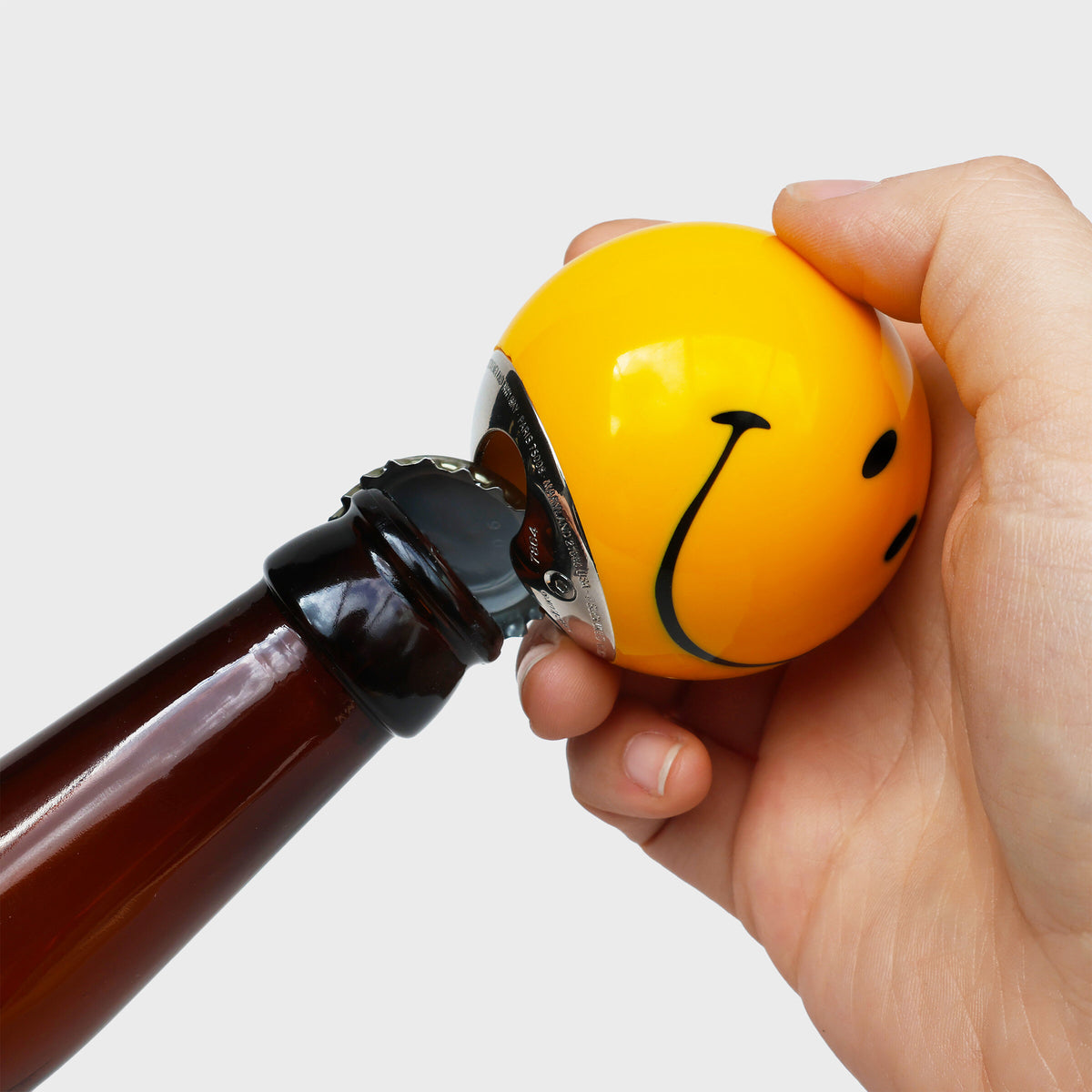 Hand opening a beer bottle with the yellow Smiley pool ball opener