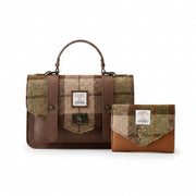 A brown and beige plaid tweed satchel bag with a top handle, shown alongside a matching small wallet on a wooden tabletop against a neutral studio background. Both items feature a white Harris Tweed label.