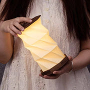 Twist Hexagon lamp walnut finish held at angle, glowing in hands