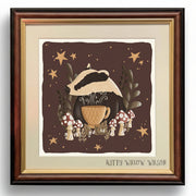 Framed art print featuring a whimsical illustration of a badger wearing a mushroom cap and holding a teacup, surrounded by mushrooms, stars, and foliage on a dark brown background. The print is mounted with a cream mat and a dark brown wood frame.