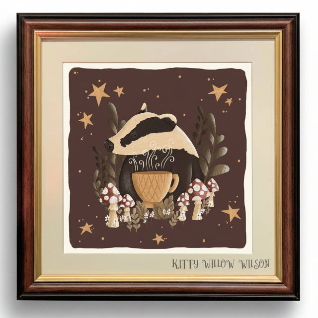 Framed art print featuring a whimsical illustration of a badger wearing a mushroom cap and holding a teacup, surrounded by mushrooms, stars, and foliage on a dark brown background. The print is mounted with a cream mat and a dark brown wood frame.
