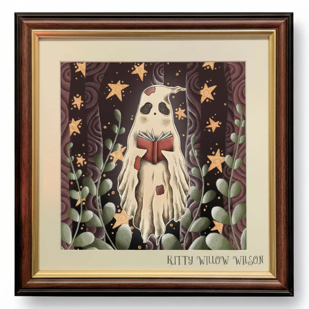 Framed art print featuring a whimsical illustration of a ghost-like figure reading a red book, surrounded by stars and green leaves on a dark background, with the text 'KITTY WILLOW WILSON' at the bottom.
