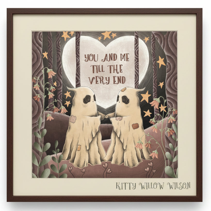 A framed art print featuring two ghost-like figures facing each other in front of a large heart-shaped moon with the text 'YOU AND ME TILL THE VERY END'. The artwork is signed 'KITTY WILLOW WISON' at the bottom.