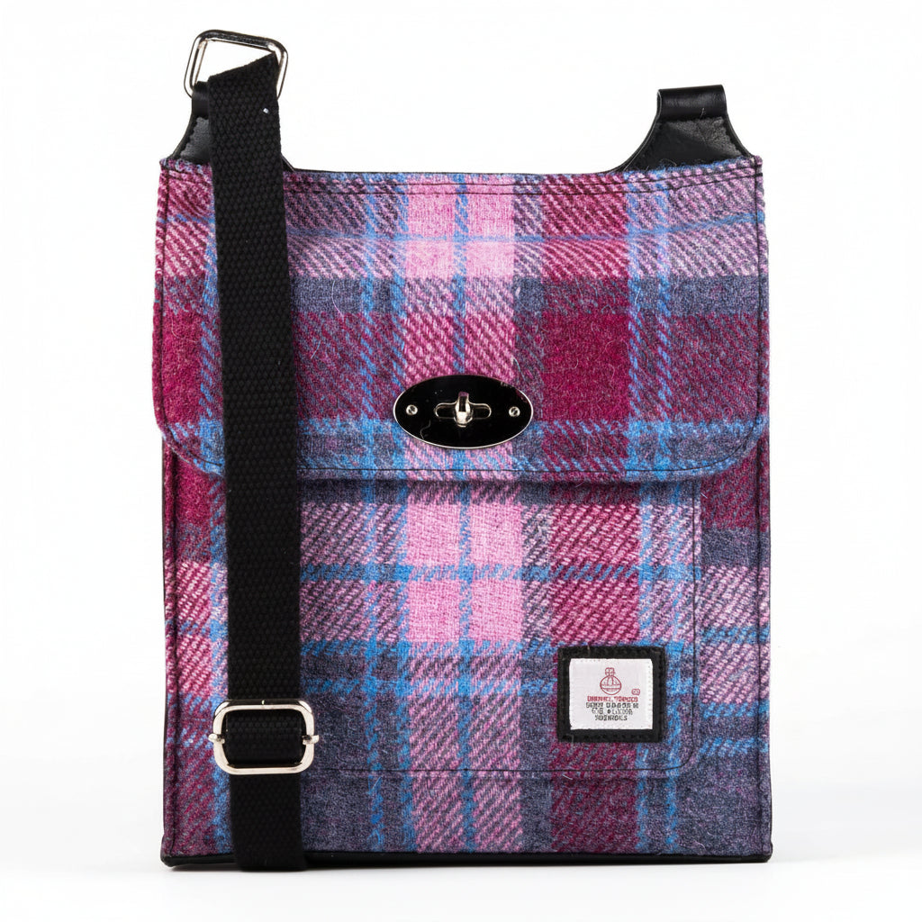 Harris Tweed satchel bag in a pink and blue check tartan design with the adjustable shoulder strap draped across the top.
