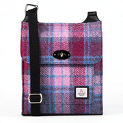 Harris Tweed satchel bag in a pink and blue check tartan design with the adjustable shoulder strap draped across the top.