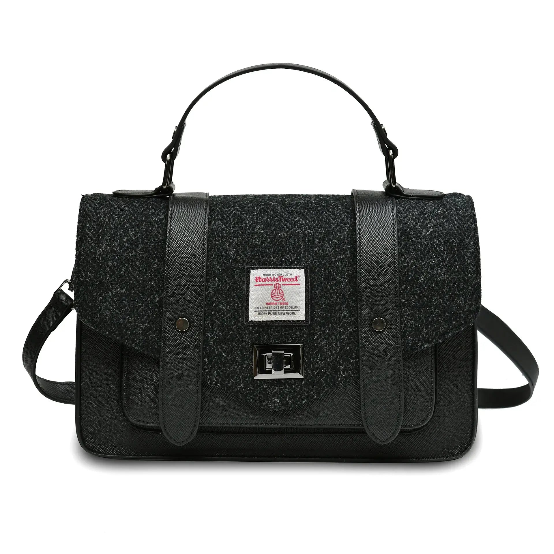 Islander Harris Tweed satchel style handbag in a Black Herringbone design. It has a black synthetic leather body and a shoulder strap lying behind. 